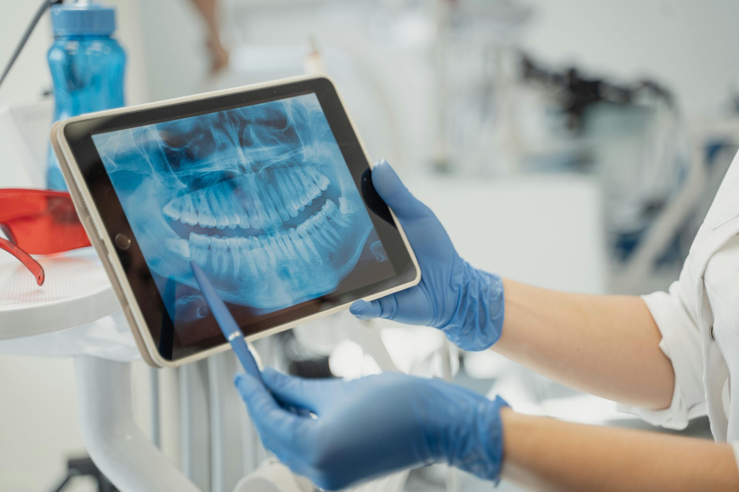 Close-up of a dentist analyzing a dental X-ray on a digital tablet in a clinic setting.